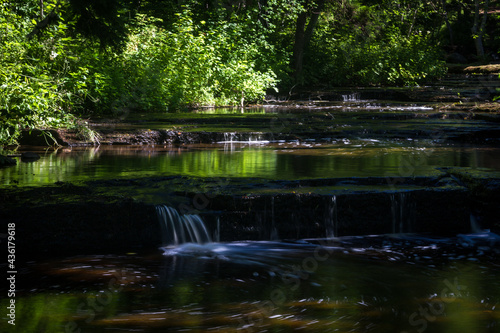 Cascading waterfall cascades in Estonia in green light at summertime