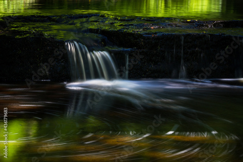 Cascading waterfall cascades in Estonia in green light at summertime