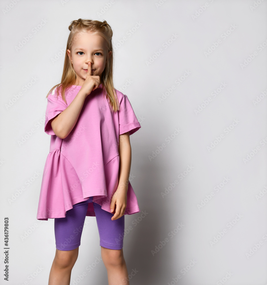 small blonde in summer clothes - legends and a wide T-shirt, pressed her finger to her mouth, hiding something, a secret. small blonde in summer clothes - legends and a wide T-shirt, pressed her finger to her mouth, hiding something, a secret.