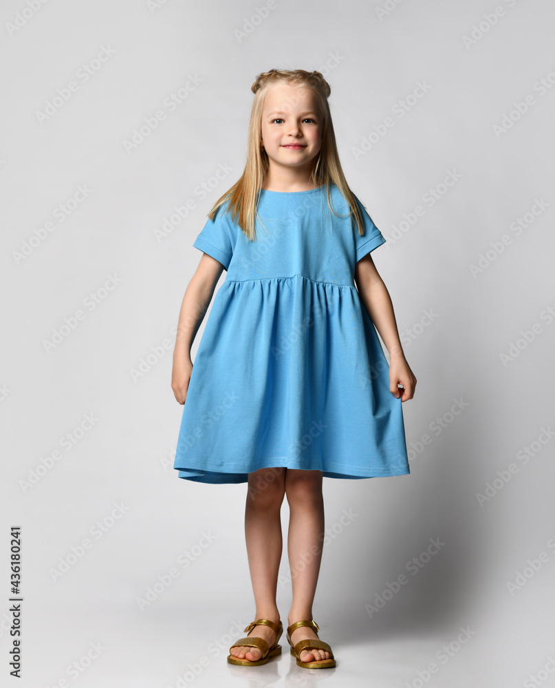 Studio portrait of a cute beautiful little girl in a blue summer dress on a white background. Kids fashion concept. New collection of summer clothes for little girls. Advertising banner. Studio portrait of a cute beautiful little girl in a blue summer dress on a white background. Kids fashion concept. New collection of summer clothes for little girls. Advertising banner.