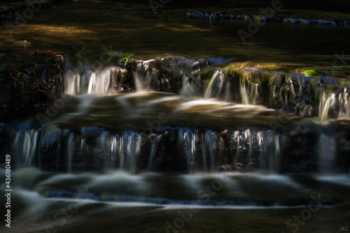 Cascading waterfall cascades in Estonia in green light at summertime