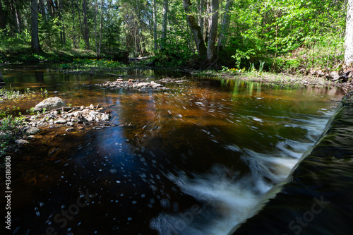 Cascading waterfall cascades in Estonia in green light at summertime