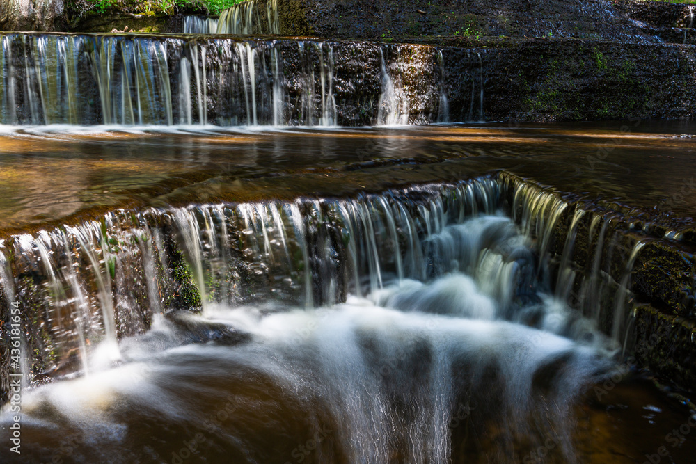 Cascading waterfall cascades in Estonia in green light at summertime
