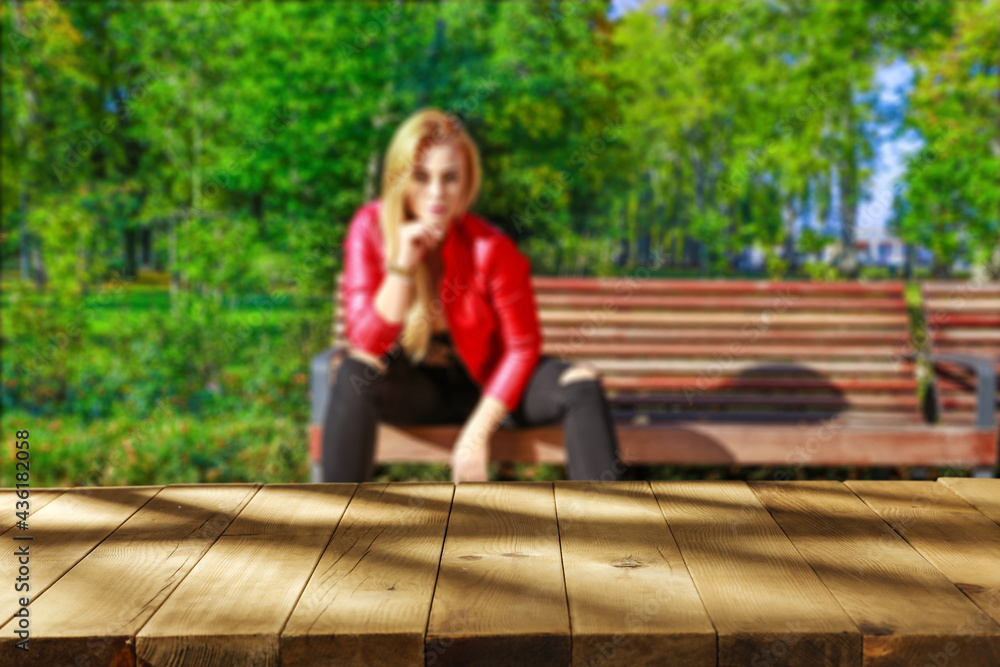 Obraz premium Slim young woman in garden and wooden desk of free space 
