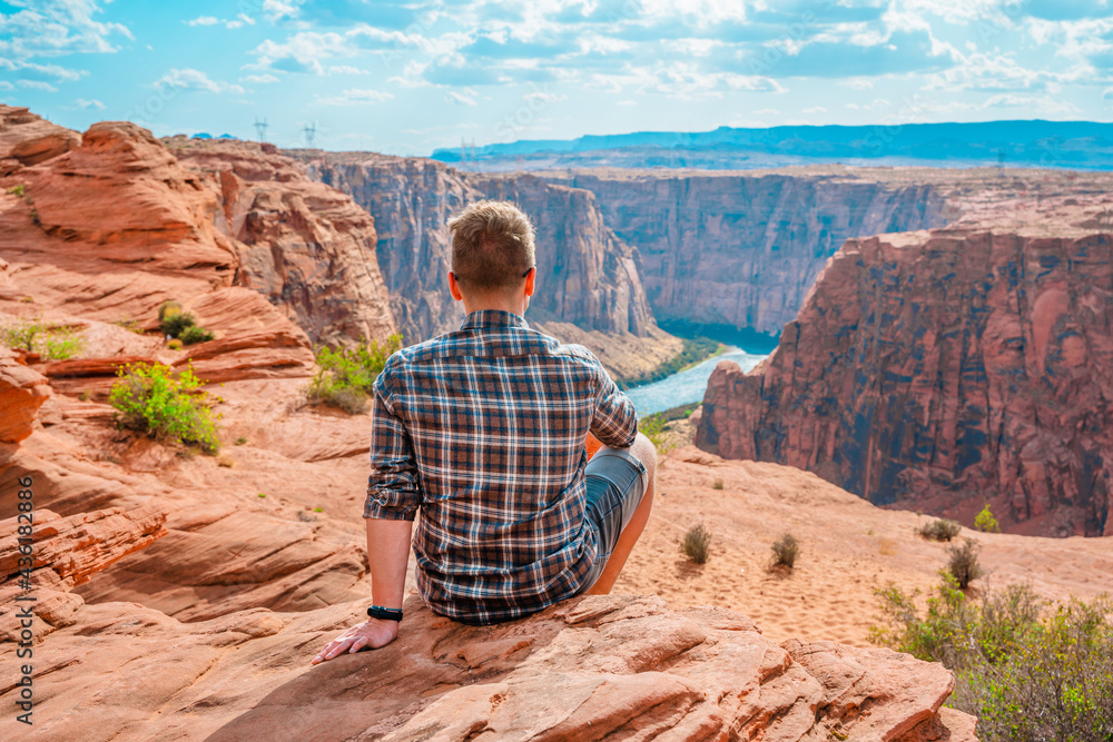 Gorgeous landscape and young man on red rocks overlooking the Colorado River, Arizona