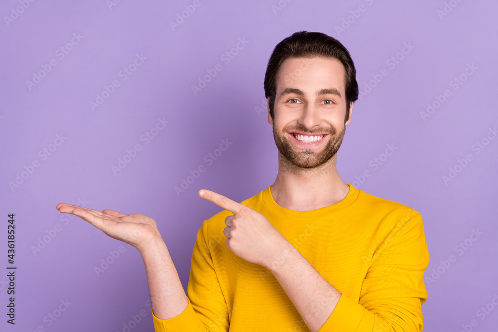 Portrait of attractive cheerful man demonstrating on palm copy space ad isolated over bright violet purple color background Portrait of attractive cheerful man demonstrating on palm copy space ad isolated over bright violet purple color background