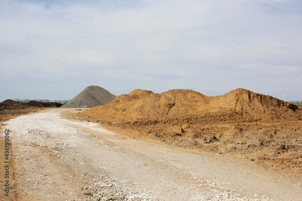 Construction of a new road. A layer of rubble was laid. Nearby are mountains of earth and sand. Close-up. Space for text.
