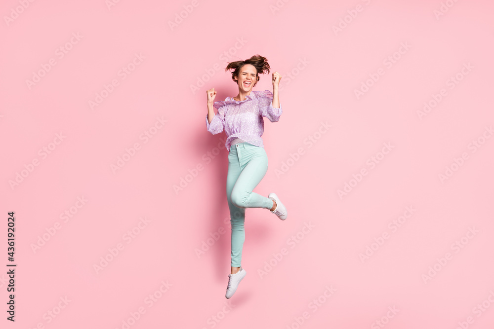 Full length photo portrait of cheerful girl celebrating jumping up isolated on pastel pink colored background Full length photo portrait of cheerful girl celebrating jumping up isolated on pastel pink colored background