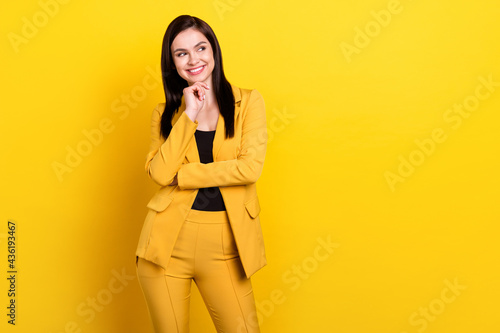 Photo of young pretty woman happy positive smile hand touch chin dream look empty space isolated over yellow color background