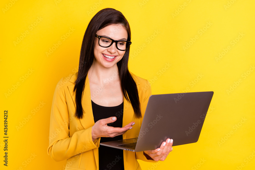 Photo of charming sweet young lady dressed formal blazer glasses smiling talking modern device isolated yellow color background Photo of charming sweet young lady dressed formal blazer glasses smiling talking modern device isolated yellow color background