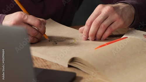 A close-up shot of a male hands drawing a skull on the paper with a pencil photo