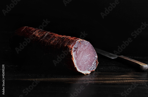 Traditionally smoked Iberian pork loin on rustic wooden table.