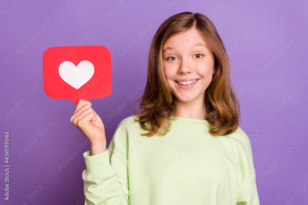 Photo of young girl happy positive smile show reaction icon like repost click heart isolated over violet color background Photo of young girl happy positive smile show reaction icon like repost click heart isolated over violet color background