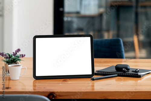 Mockup blank screen tablet and gadget on wooden table in office room with copy space.