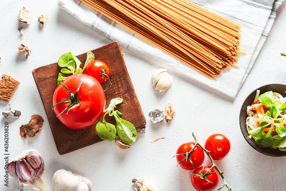 Juicy tomato with pasta and vegetables on bright background. Spaghetti base. - obrazy, fototapety, plakaty 