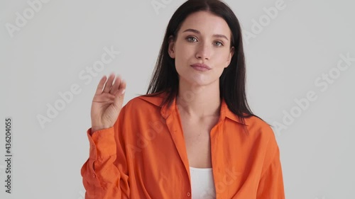 A displeased woman is showing blablabla sign showing nonsense content something standing isolated over grey wall in the studio photo