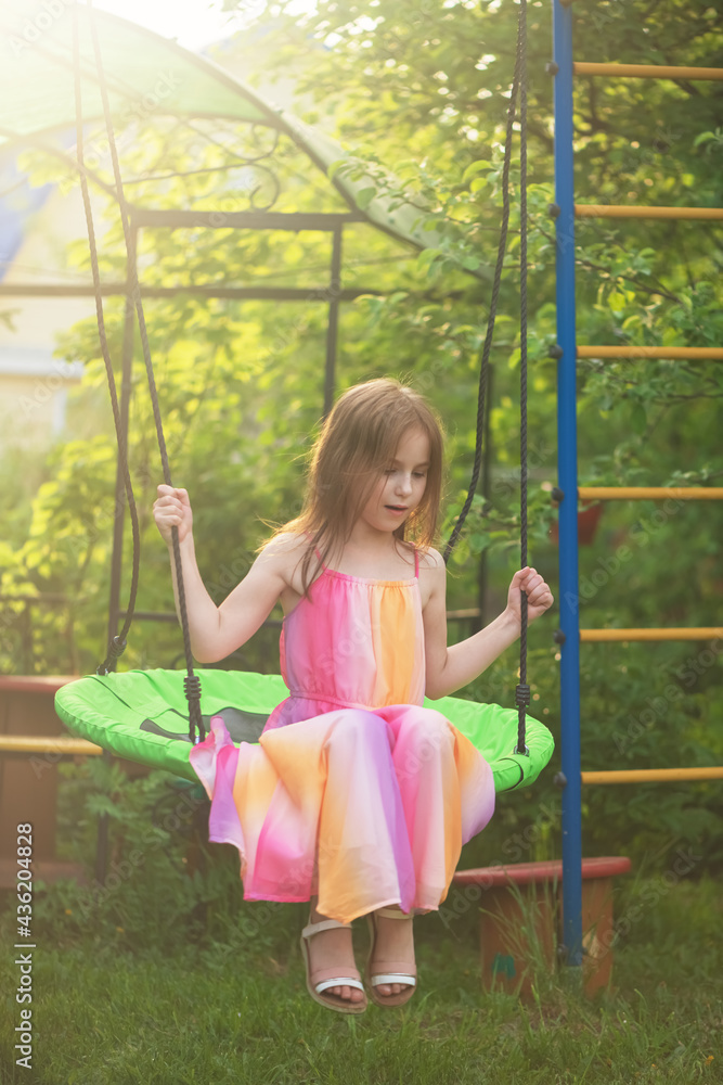 Cute girl in a beautiful summer dress swings on the swing Cute girl in a beautiful summer dress swings on the swing