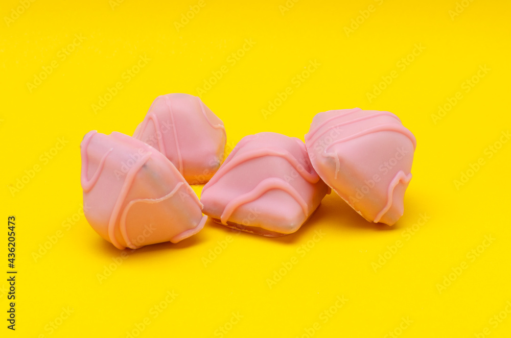Closeup of pile of sweet pink candies on the bright yellow background Closeup of pile of sweet pink candies on the bright yellow background