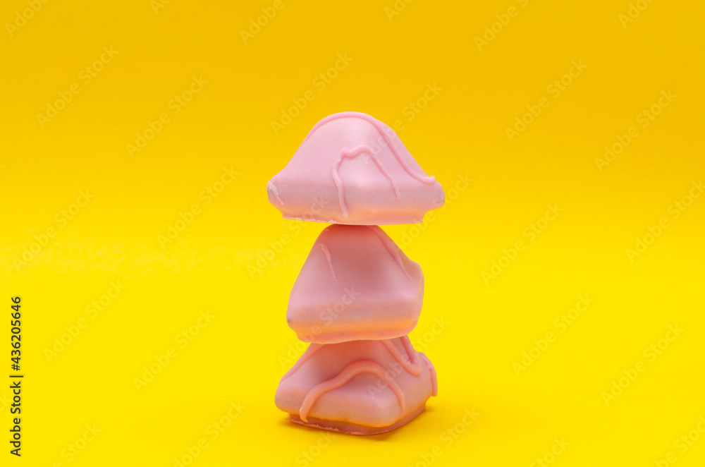 Stack of three sweet pink candies on the bright yellow surface