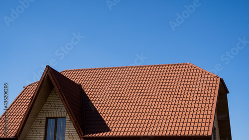 Red corrugated metal profile roof installed on a modern house. The roof of corrugated sheet. Roofing of metal profile wavy shape. Modern roof made of metal. Metal roofing.