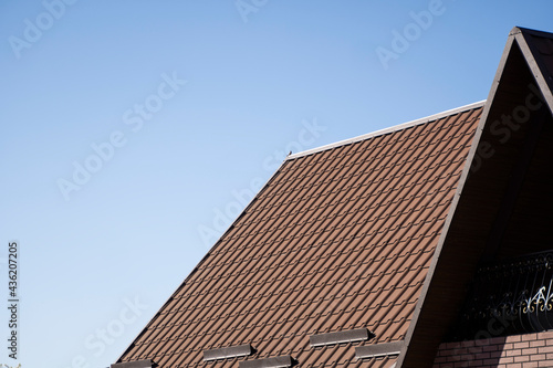 Brown corrugated metal profile roof installed on a modern house. The roof of corrugated sheet. Roofing of metal profile wavy shape. Modern roof made of metal. Metal roofing.