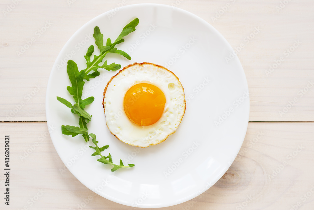 Fried eggs with arugula in a plate. Horizontal orientation, top view. Fried eggs with arugula in a plate. Horizontal orientation, top view.