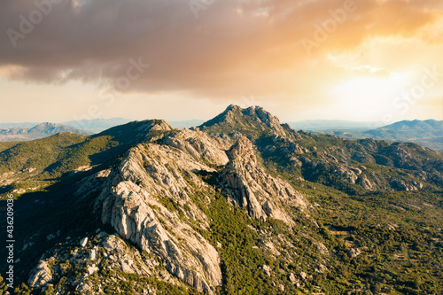 Obraz na płótnie View from above, stunning aerial view of a valley surrounded by some granite mountains and green vegetation during a beautiful sunset. San Pantaleo, Sardinia, Italy. w salonie