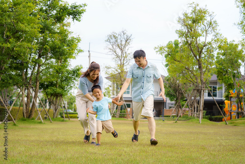 Asian family playing catch on yard or public park in neighborhood for daily health and well being, both physical and mental happy family.