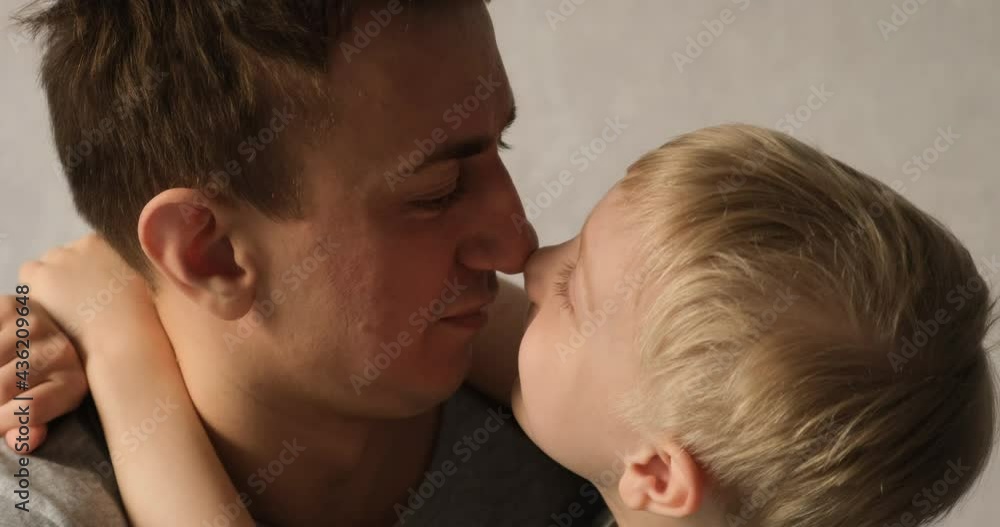 Dad and son rub their noses on each other, the boy tells something. Kid hugs daddy. Tenderness between parent and child Dad and son rub their noses on each other, the boy tells something. Kid hugs daddy. Tenderness between parent and child
