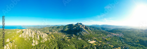 Obraz na płótnie View from above, stunning aerial view of San Pantaleo village surrounded by some granite mountains, green vegetation and the mediterranean sea in the distance. Sardinia, Italy. w salonie