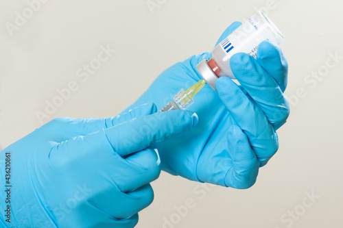 hand in glove with gloves and filler vial
