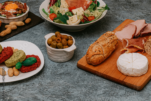 Meat platter and Camembert cheese with baguette. Salad with prosciutto. Olives. Perfect fried eggs with mushrooms and spices. Vegan vegetable cutlets and peanuts. Fork. Food delivery.