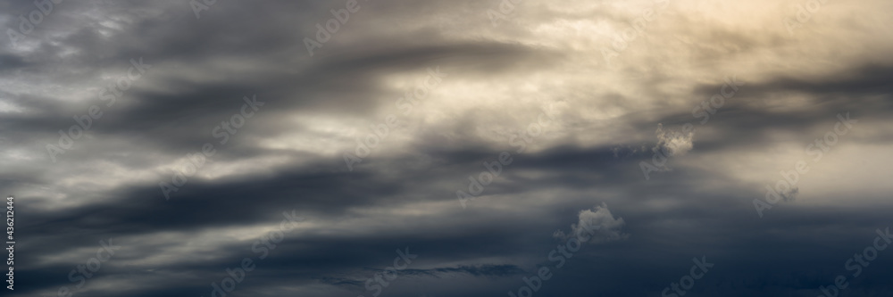 wide panoramic view of dramatic cloudy sky with back sunlight