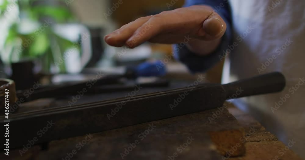 Caucasian female jeweller in workshop wearing apron, using gas burner, melting metal Caucasian female jeweller in workshop wearing apron, using gas burner, melting metal