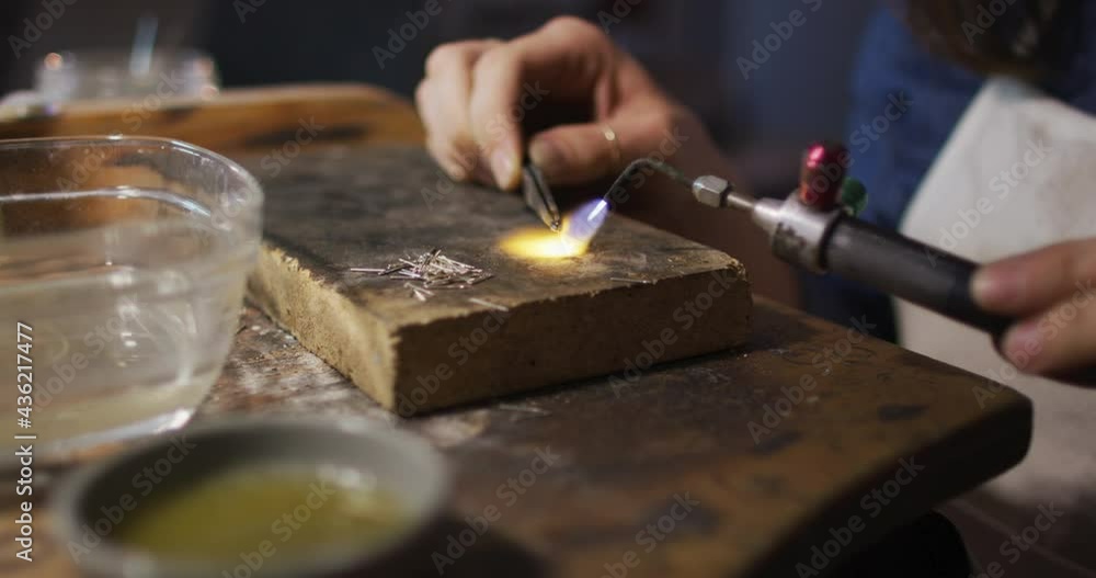 Close up of hands of caucasian female jeweller using gas burner, making jewelry Close up of hands of caucasian female jeweller using gas burner, making jewelry