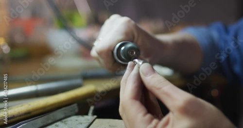 Close up of hands of caucasian female jeweller using tools, making jewelry photo