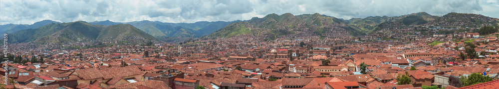 Panoramic photo aerial of rooftops in Cusco city. Tile roofs in a valley surrounded by green. Peru, South America