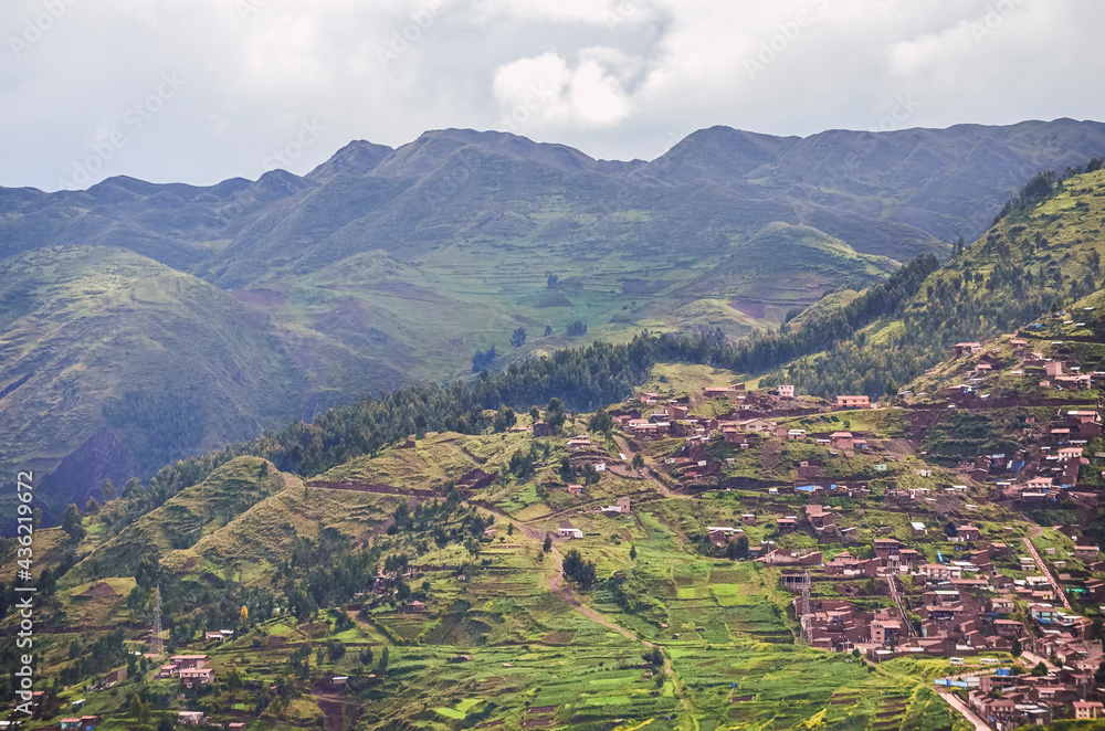 Aerial view of rooftops and houses on the hills of Cusco city surrounded by green fields and mountains. Houses and structures from a fair away point. Peru, South America Aerial view of rooftops and houses on the hills of Cusco city surrounded by green fields and mountains. Houses and structures from a fair away point. Peru, South America
