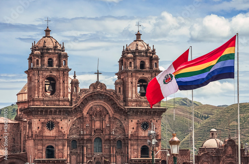 Cusco Cathedral view with peruvian and wiphala flags waving and floating with the wind. Photo from main city square of Cusco with green hills and sky in the bottom. Peru, South America photo