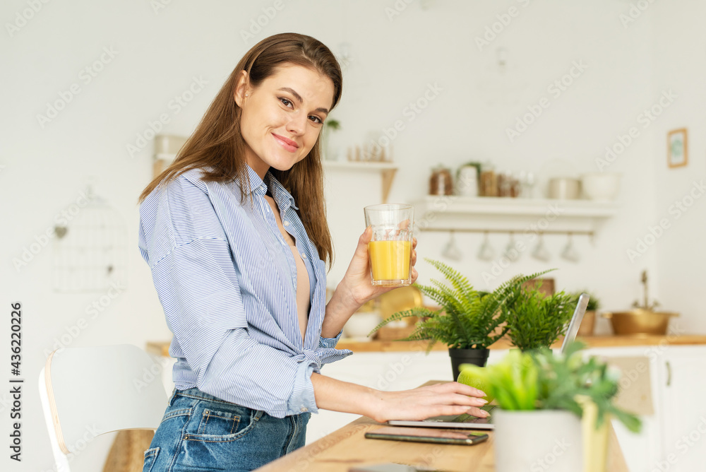 Photo of a positive woman using a laptop, in her free time, using a smartphone and surfing social networks, at home indoors. Young woman working with laptop computer, concentrated and smiling for the Photo of a positive woman using a laptop, in her free time, using a smartphone and surfing social networks, at home indoors. Young woman working with laptop computer, concentrated and smiling for the