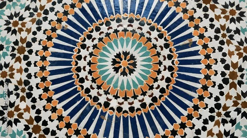 Colorful star-shaped pattern in traditional Islamic geometric design from a public fountain in Marrakech, Morocco. Made with natural colors from indigo, saffron, mint, kohl. Camera movement: rotating.