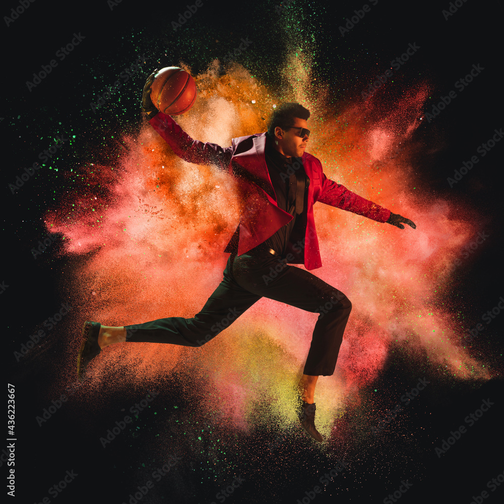Φωτογραφία One young sportsman basketball player in explosion of colored neon powder isolat