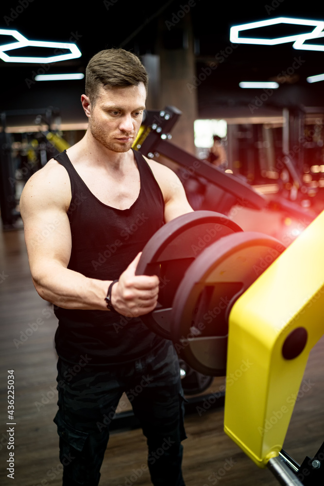 Muscular handsome man working out in the gym. Sporty strong male bodybuilding.