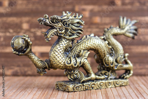 Bronze dragon on a wooden background. Statuette.
