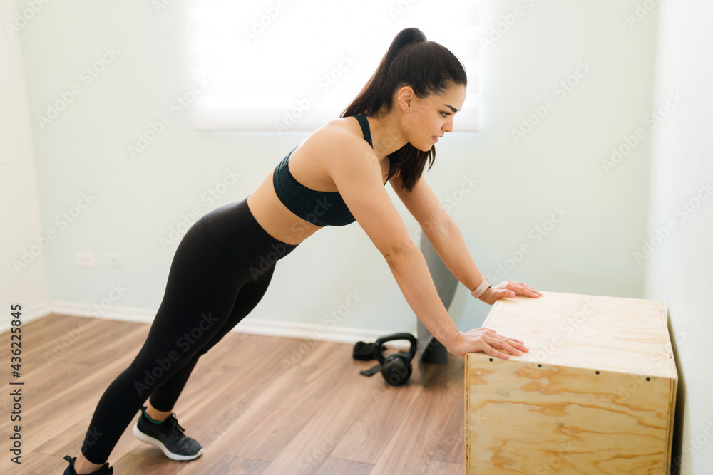 Happy young woman doing push-ups on a plyo box Happy young woman doing push-ups on a plyo box