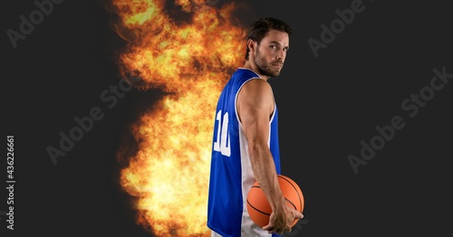 Composition of caucasian male basketball player holding ball with fire and copy space