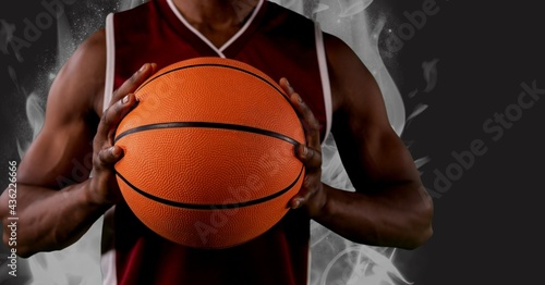 Composition of midsection of african american male basketball player holding ball with copy space