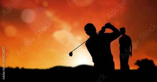 Composition of silhouette of golf players over orange sky with copy space