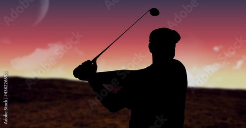Composition of silhouette of male golf player over landscape and pink sky with copy space
