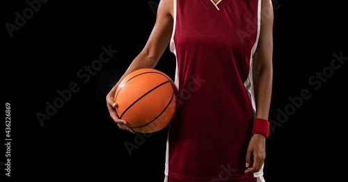 Composition of midsection of female basketball player with ball and copy space on black background